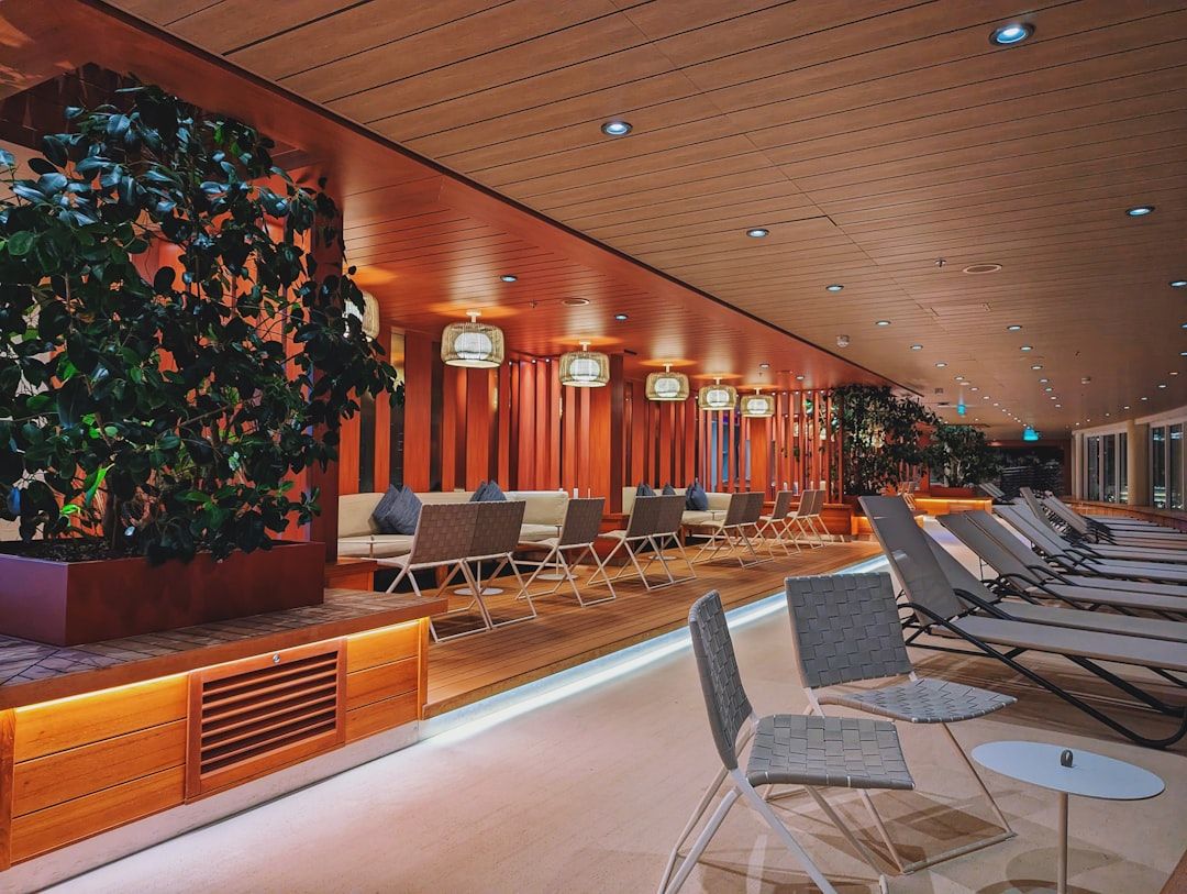 Lång, modern lounge med bekväma stolar och växter i ett kontorshotell.