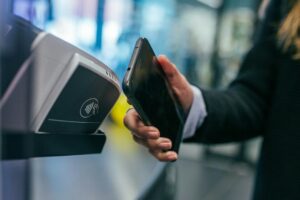 Person håller en smartphone intill en kontaktlös kortterminal